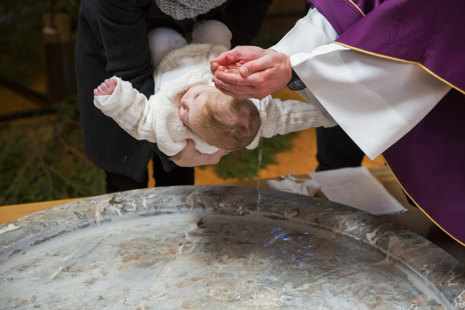 Priest is baptizing little baby girl in a church